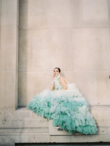 A beautiful woman wears an ombré ruffled dress that cascades in shades of muted green